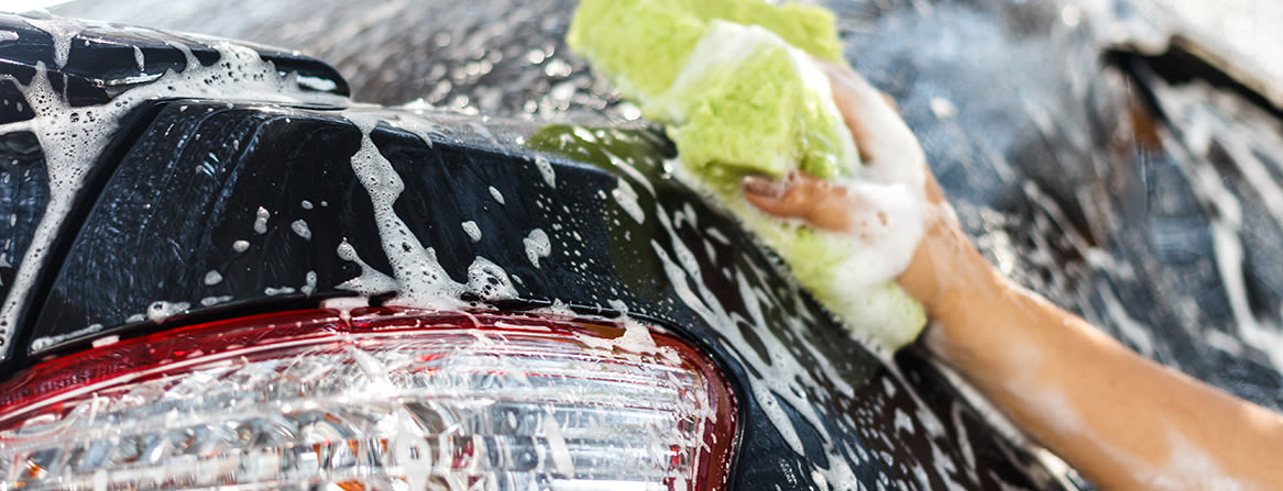 Mustan auton käsinpesu vaahdolla ja pesusienellä.