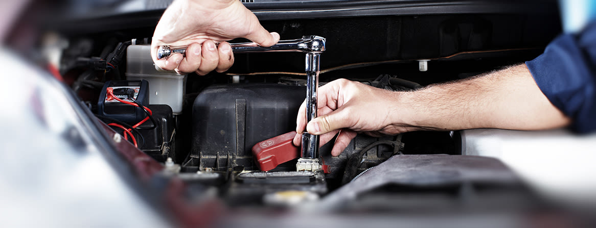 Kädet kiristävät mutteria auton moottoritilassa hylsyavaimella.