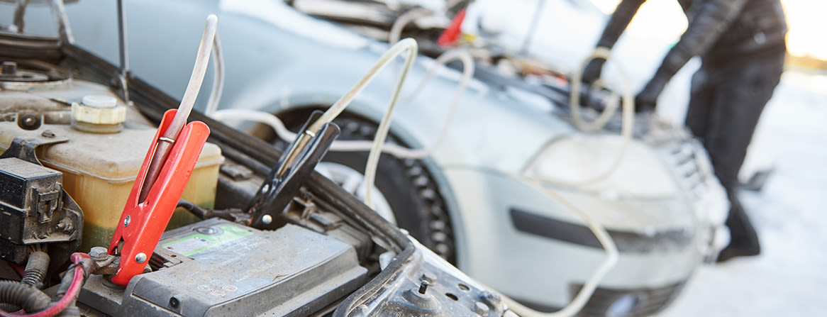 Käynnistyskaapelit yhdistetty kahden auton välillä talviolosuhteissa.