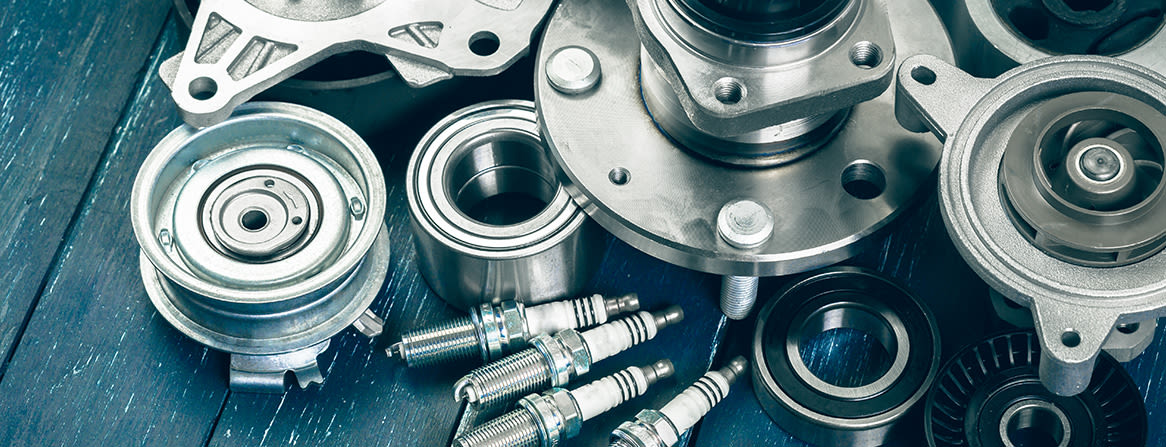 Pyöränlaakerit, sytytystulpat ja muut auton varaosat lähikuvassa.